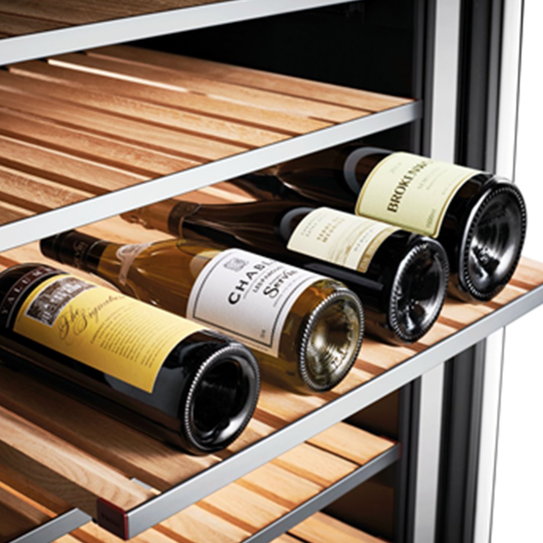 Four wine bottles resting on wooden shelves inside a wine cabinet