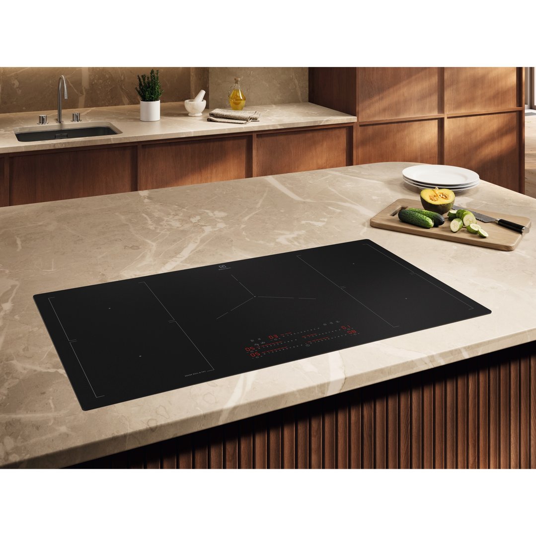 Electrolux induction cooktop built into a light marble kitchen island with food prep