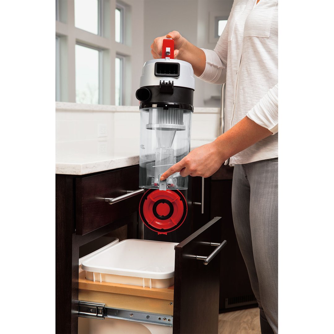 Person emptying a BISSELL Powerforce Helix TURBO Upright Vacuum Cleaner into a bin