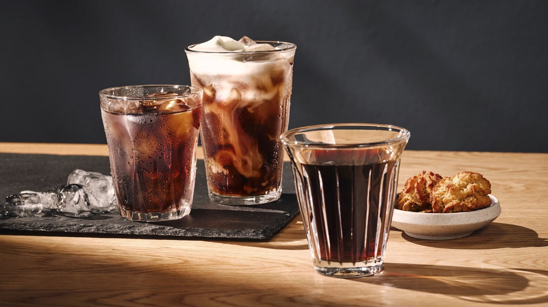 Three glasses of iced coffee and cookies on a wooden table