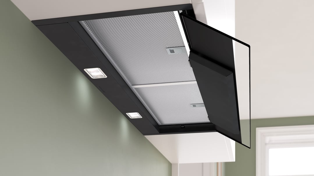 Black integrated rangehood with lights on, installed in a kitchen setting