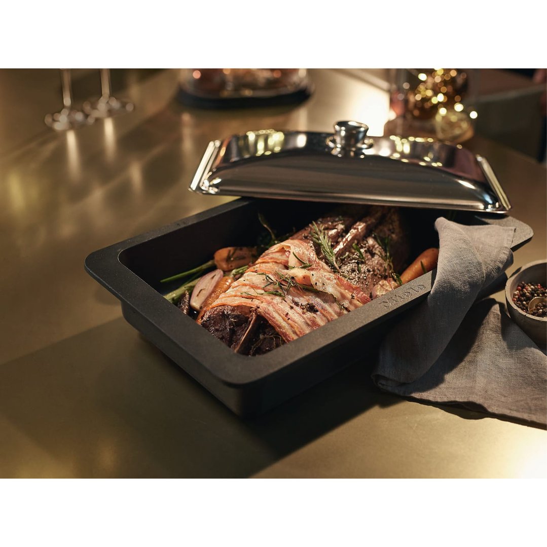 Roast with bacon and vegetables in a black roasting pan with lid