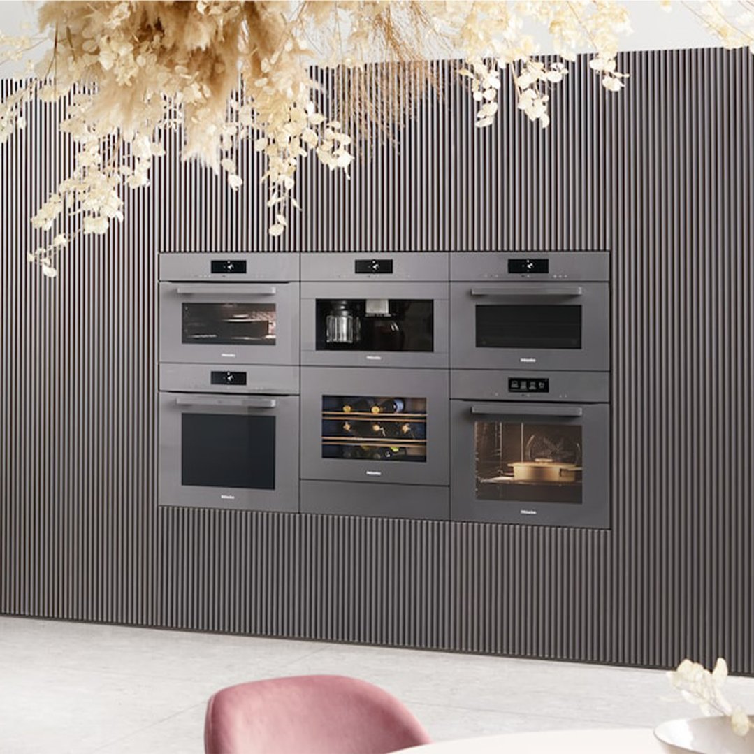 Multiple graphite grey Miele ovens and appliances built into a textured wall