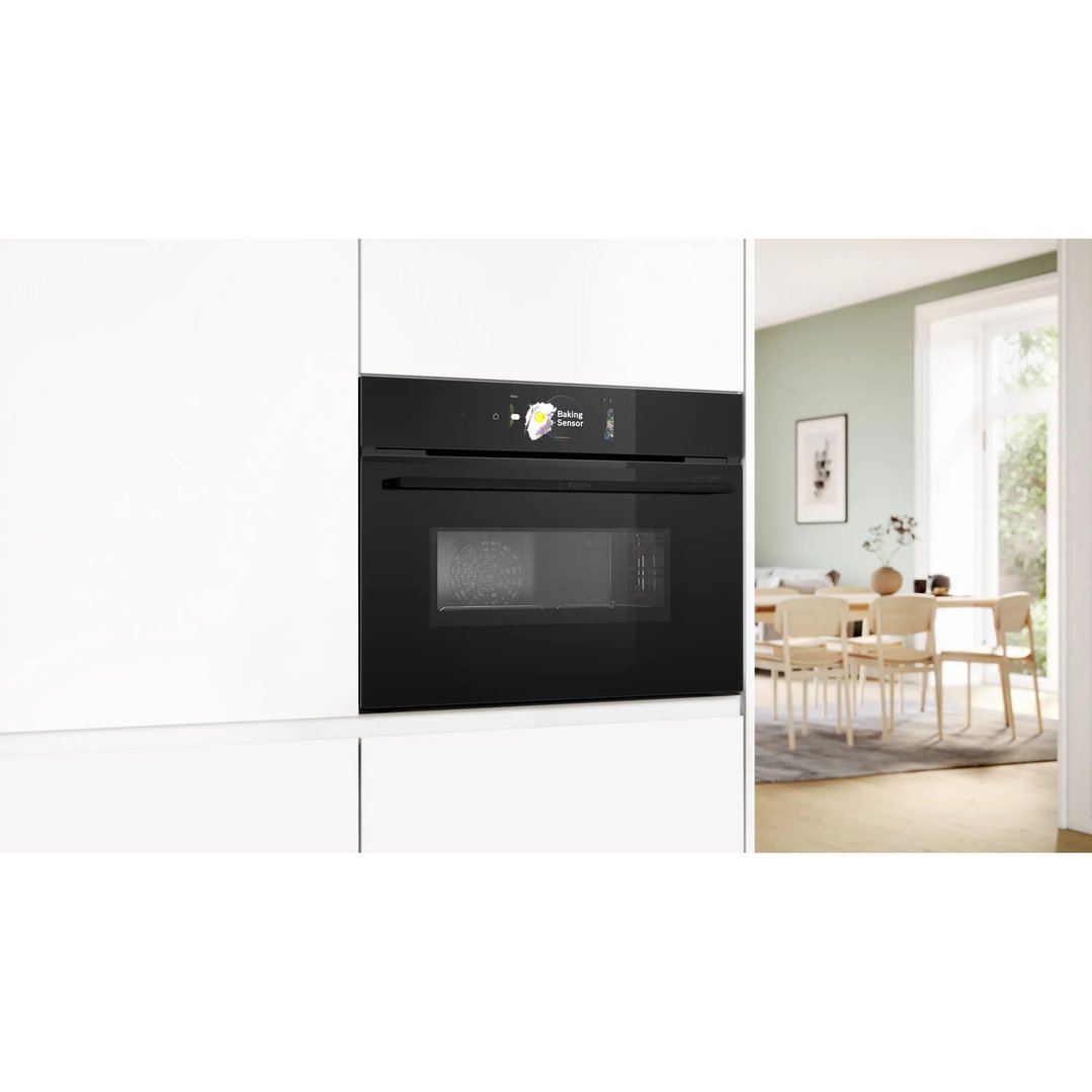 Black built-in combination oven with microwave in a white kitchen with dining area