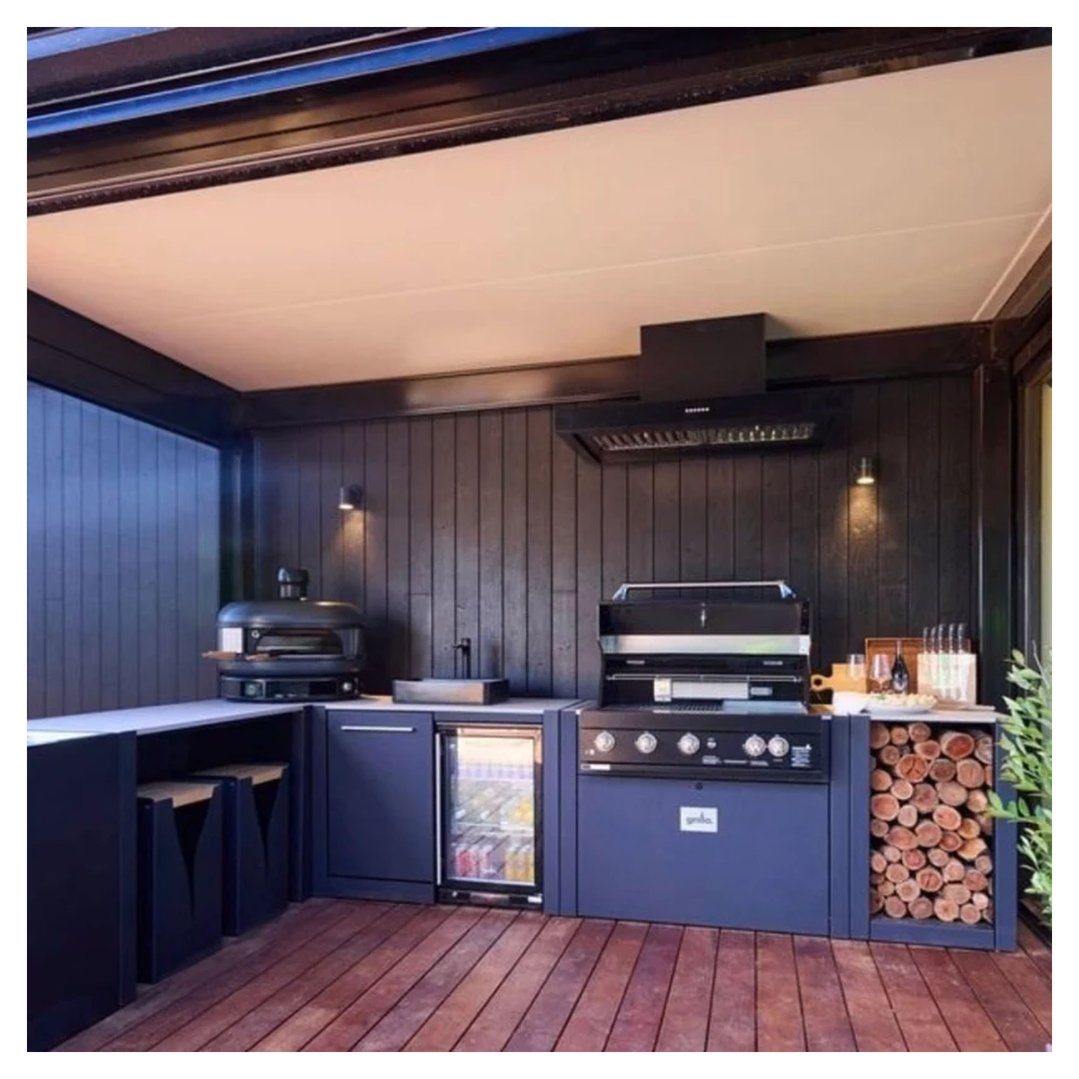 Black rangehood installed above a BBQ in an outdoor kitchen with dark cabinetry