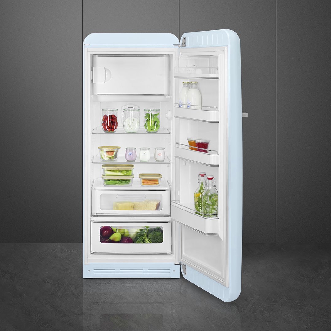 Open pastel blue Smeg refrigerator filled with food in a dark kitchen
