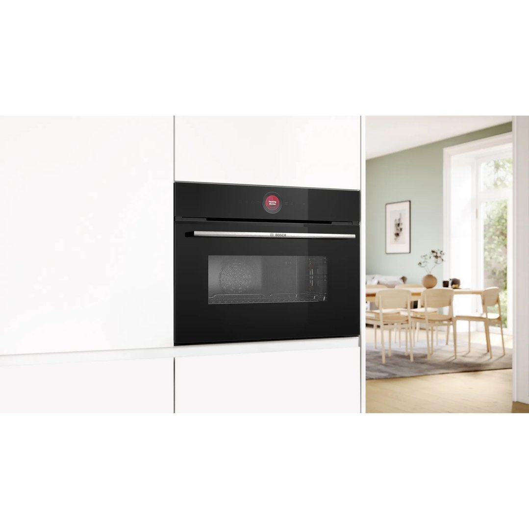 A built-in Bosch microwave oven in a white kitchen with a dining room