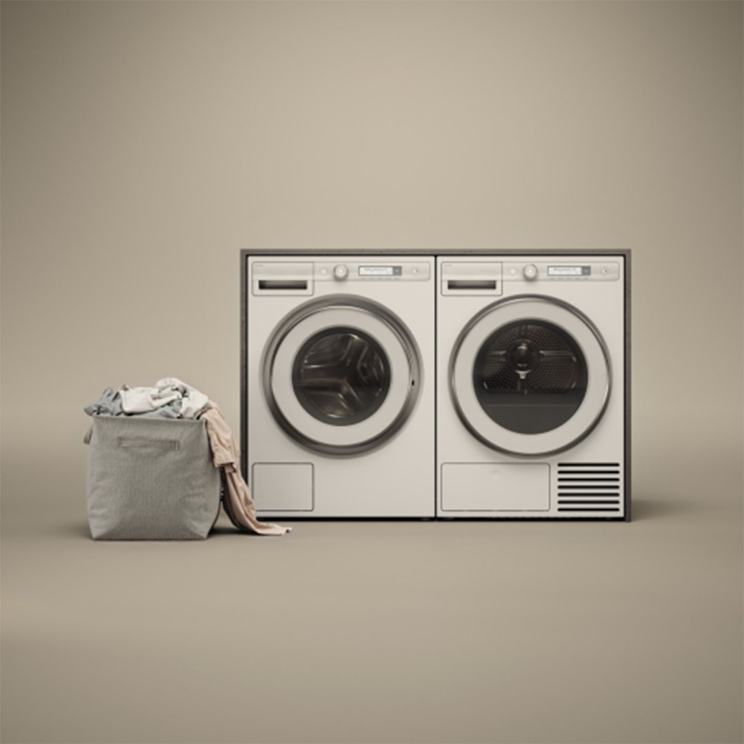 Two white ASKO dryers side-by-side with a laundry basket full of clothes
