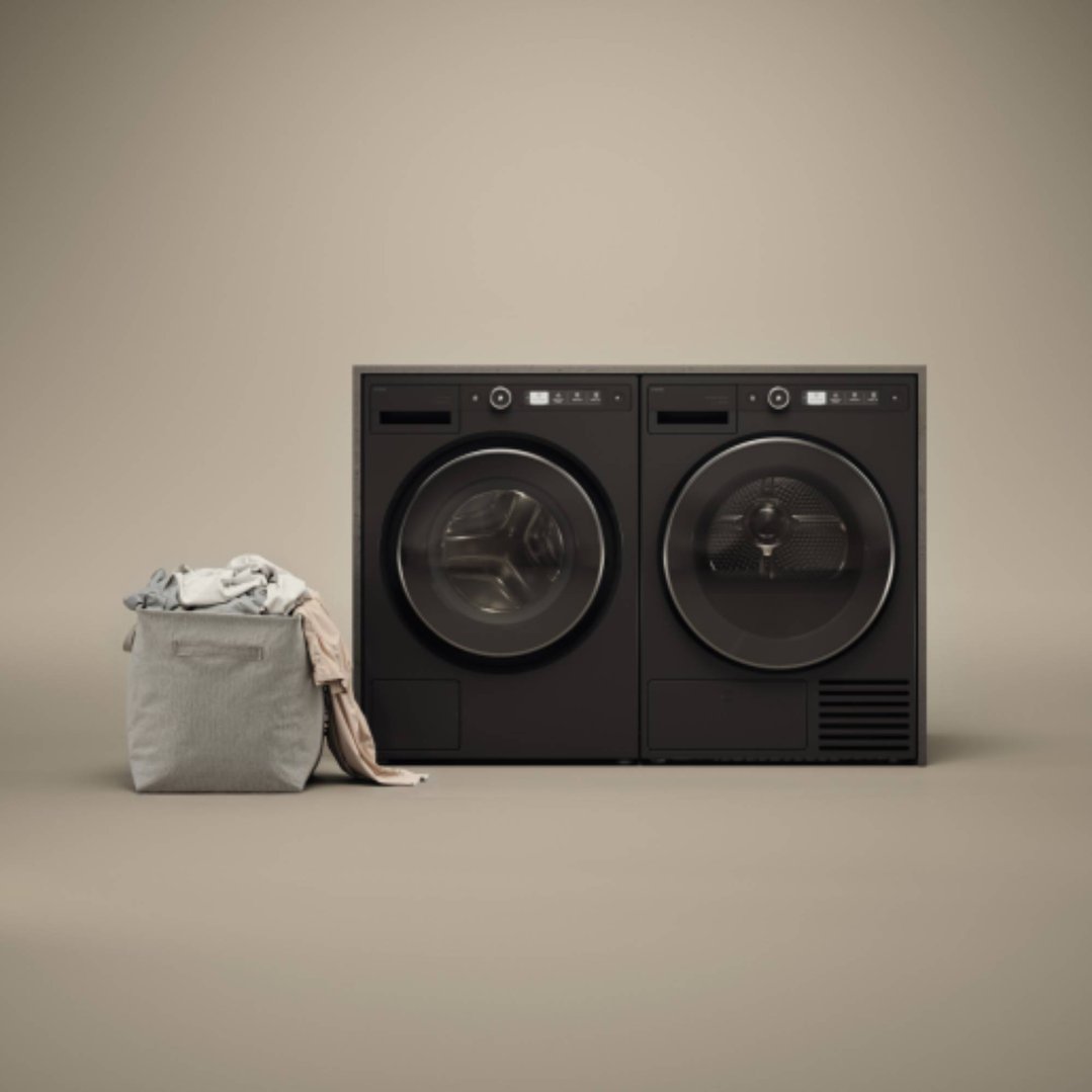 Two black dryers next to a laundry basket filled with clothes