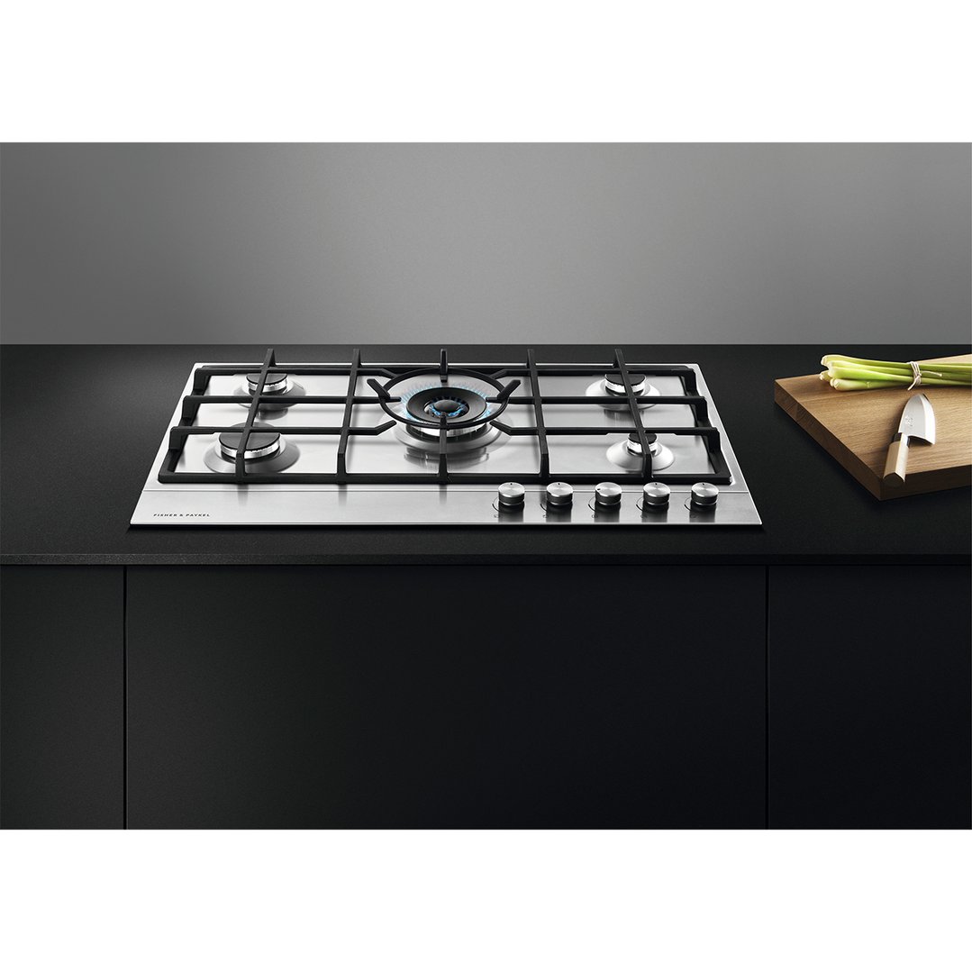 Stainless steel gas cooktop with five burners in a modern kitchen setting