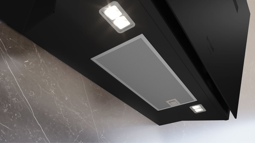 Close up of a black Siemens rangehood with lights on, mounted above a marble wall