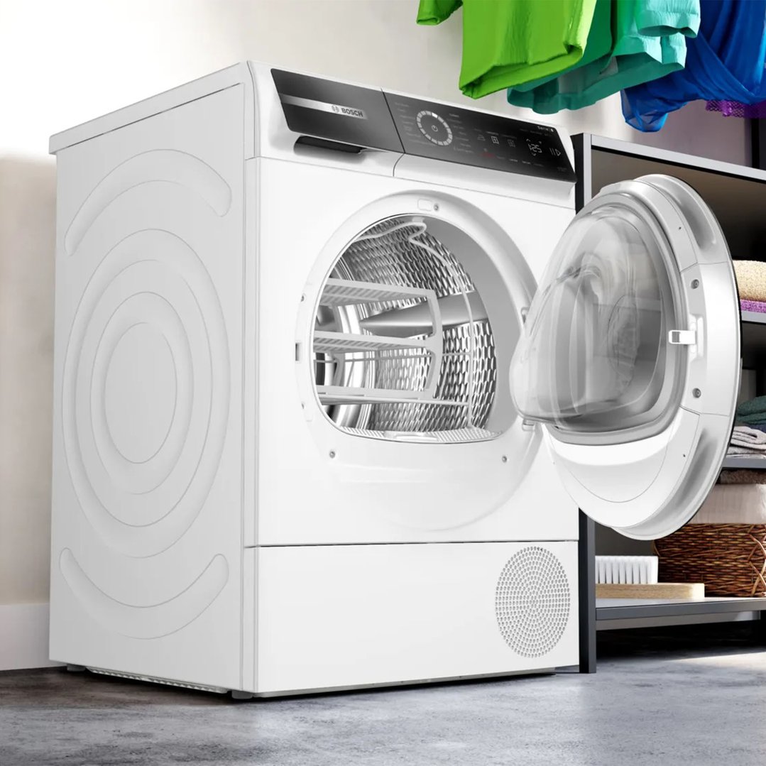 White Bosch heat pump dryer with door open in a laundry setting
