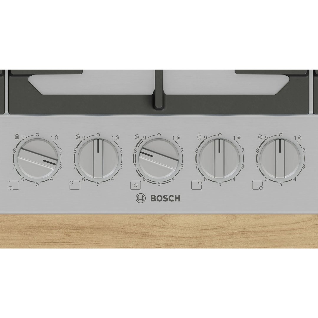 Close-up of the cooktop's control knobs on a wooden countertop