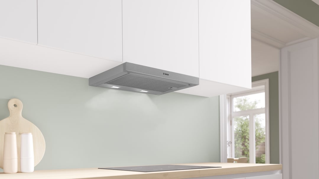 A silver metallic Bosch rangehood installed above an induction cooktop in a kitchen