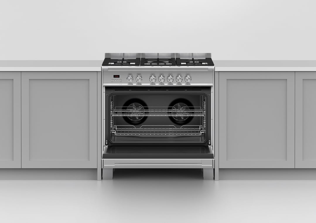 Stainless steel dual fuel cooker with open oven door in a kitchen setting
