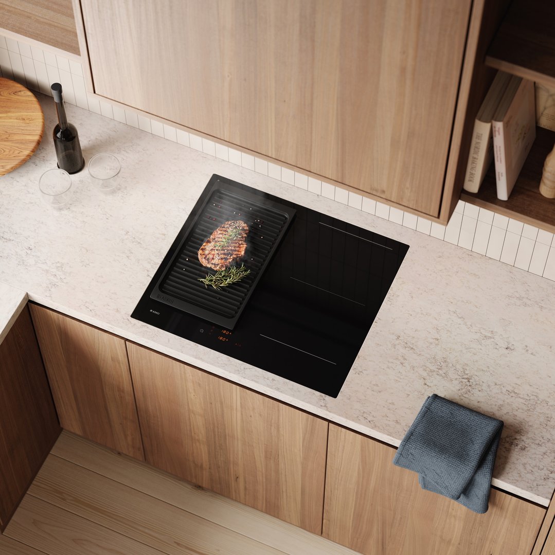 Induction cooktop with a grill pan cooking steak in a modern kitchen
