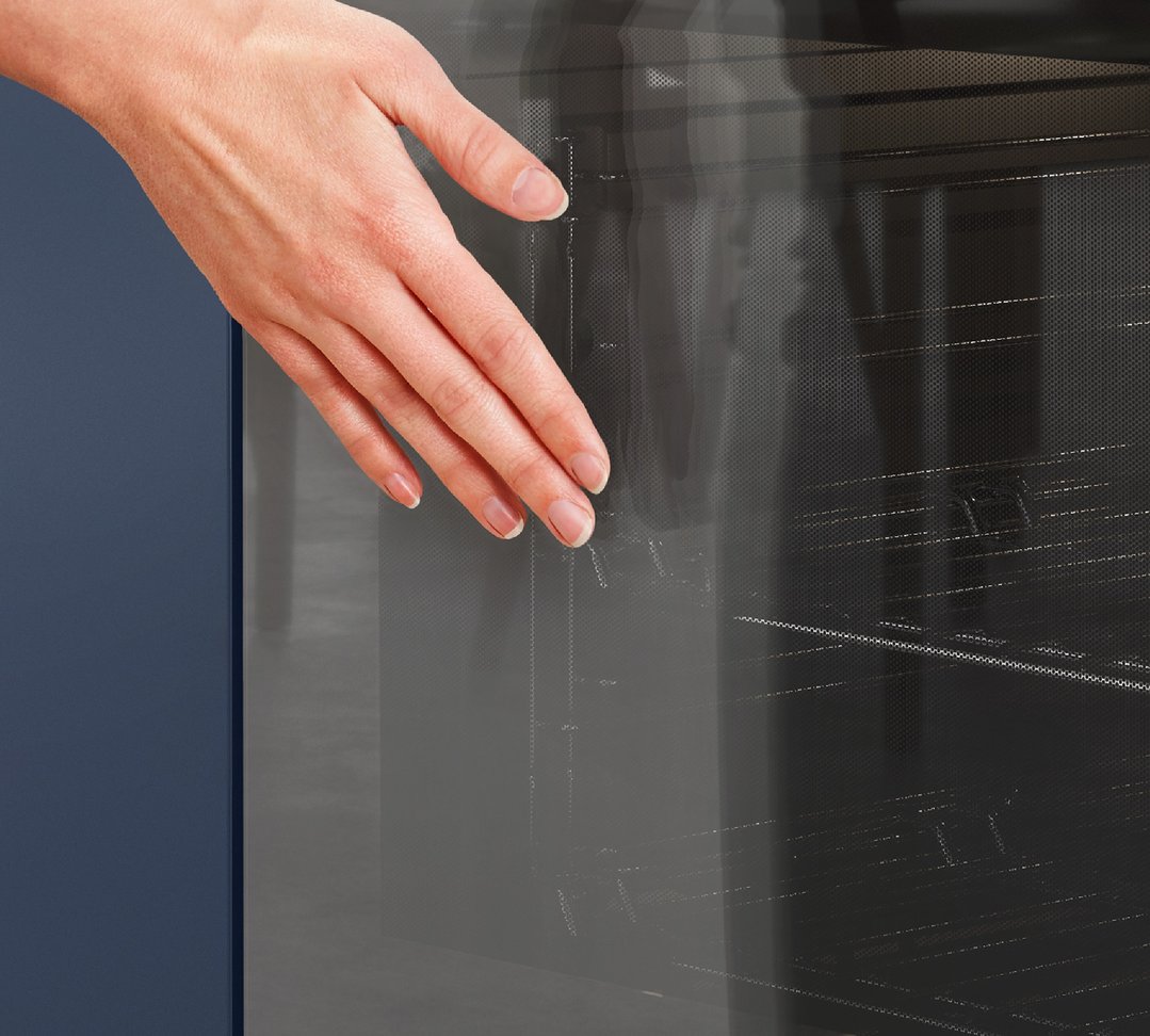 A hand reaching into a Westinghouse oven with a dark blue cabinet