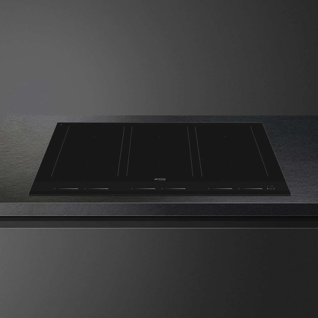 Black induction cooktop integrated into a dark countertop in a modern kitchen