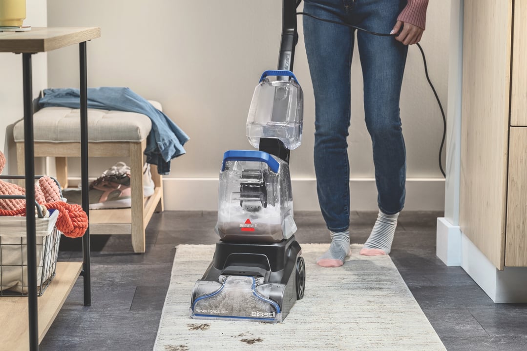 Woman cleaning a rug with a carpet cleaner in a home setting