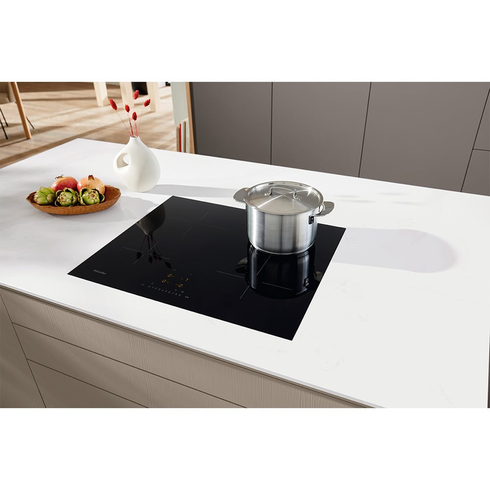 Miele induction cooktop with a pot on it, in a modern kitchen setting