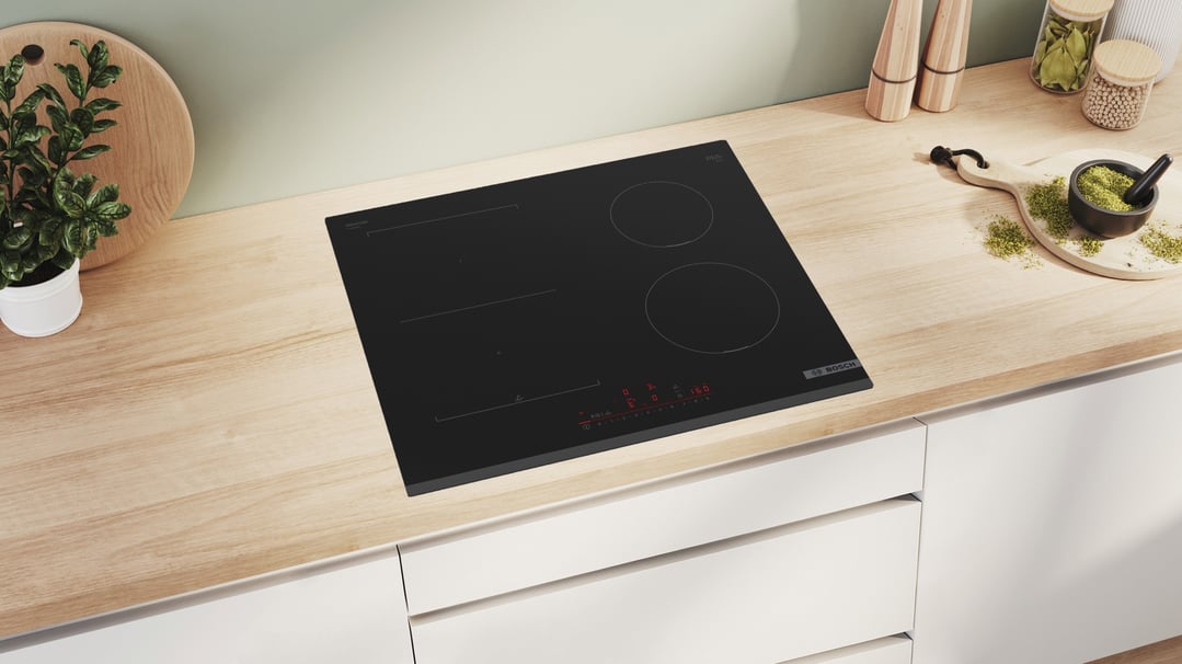 Black Bosch induction cooktop in a kitchen with wooden countertop and plants