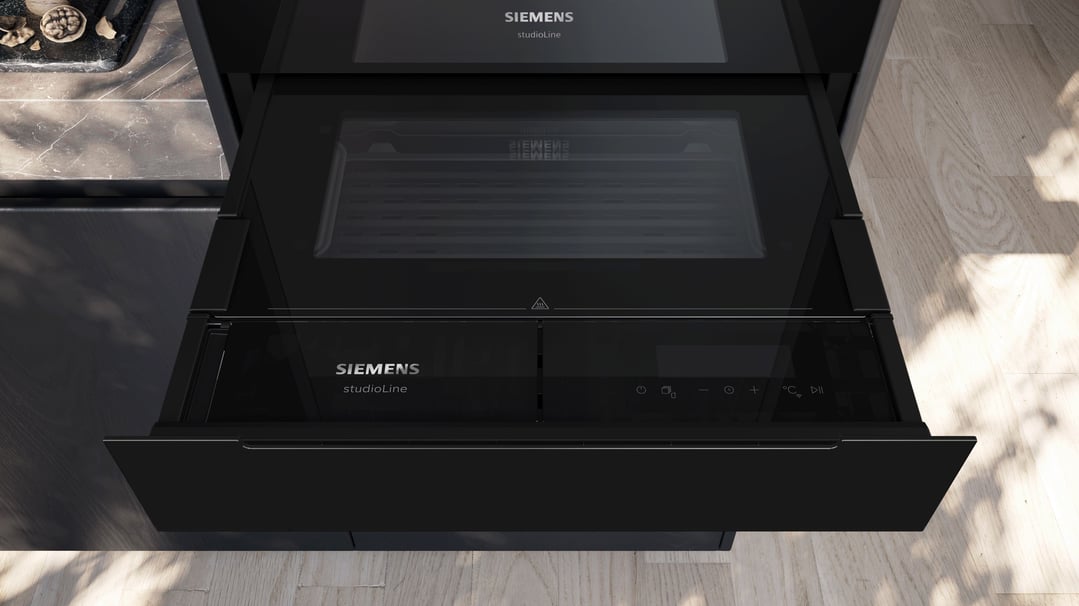 A Siemens studioLine warming drawer partially open in a modern kitchen