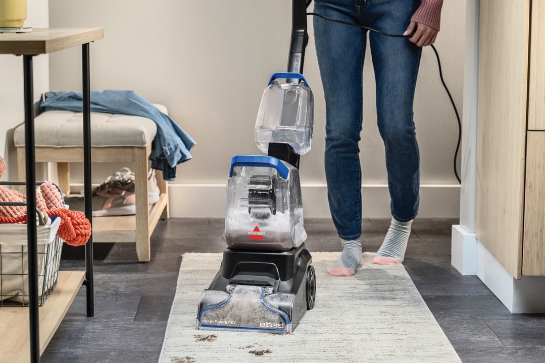Woman cleaning a rug with a BISSELL PowerForce Pet upright carpet cleaner