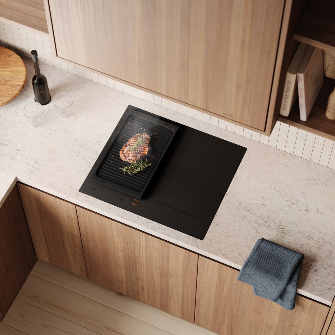 Overhead view of an ASKO induction cooktop with a steak grilling in a modern kitchen