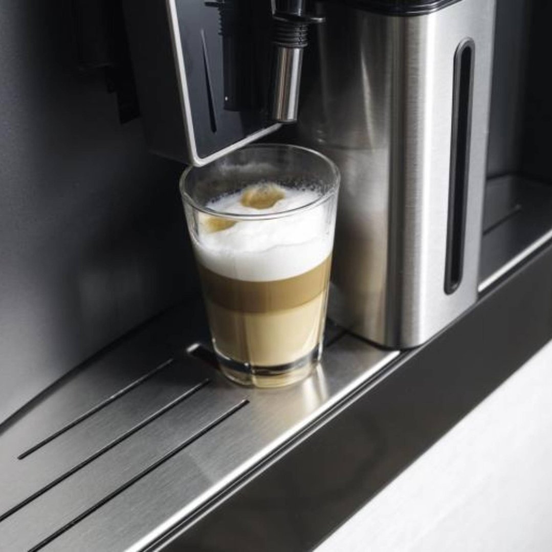 Built-in coffee machine dispensing a layered latte into a glass