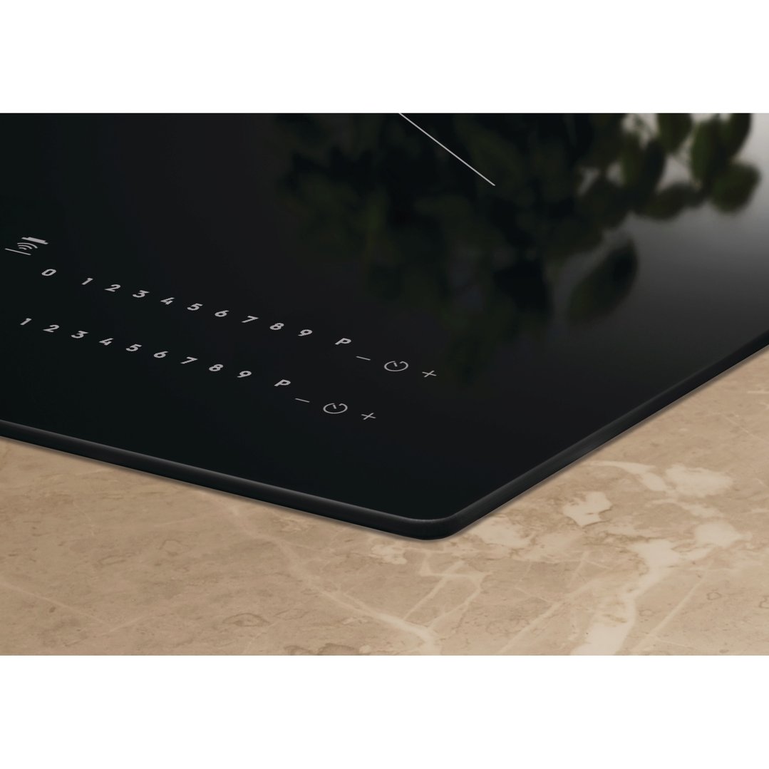 Close-up of a black induction cooktop with controls on a marble countertop