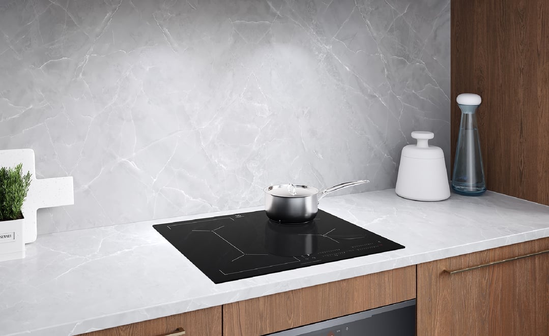 A stainless steel pot on a black induction cooktop in a modern kitchen