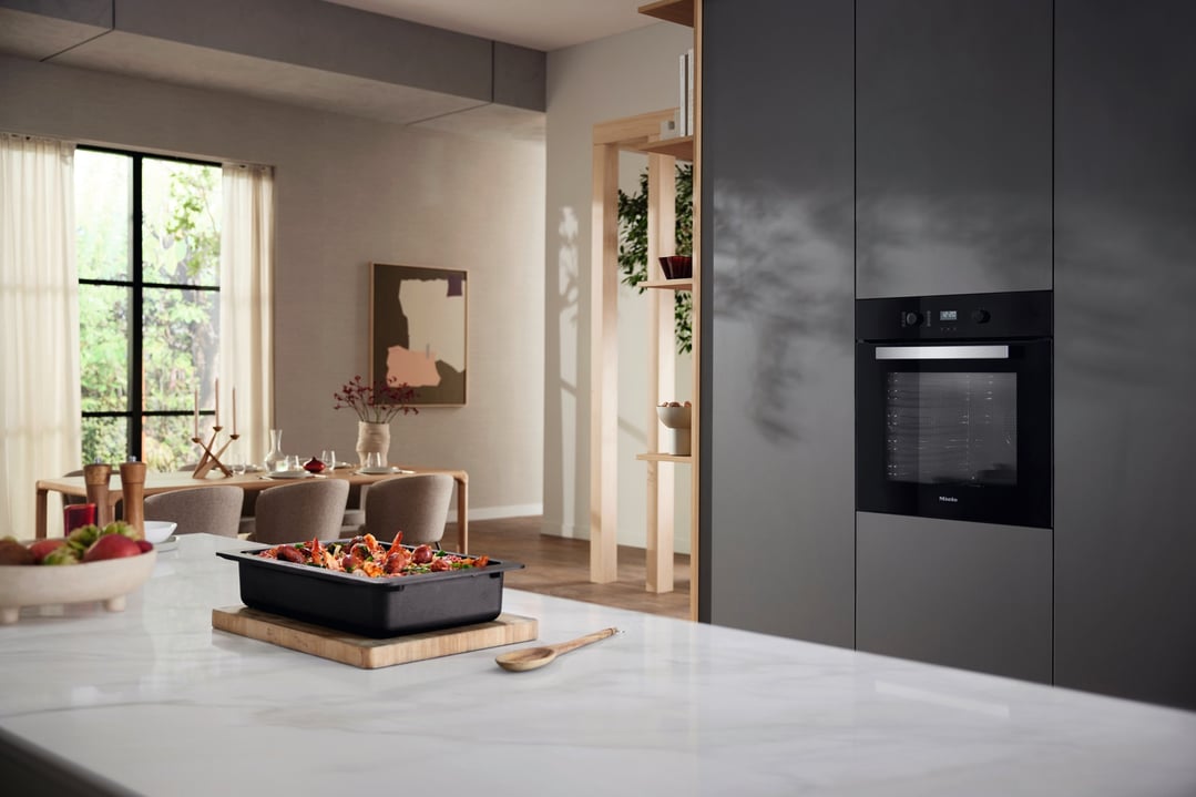 Black built-in oven in a modern kitchen with food on a marble countertop