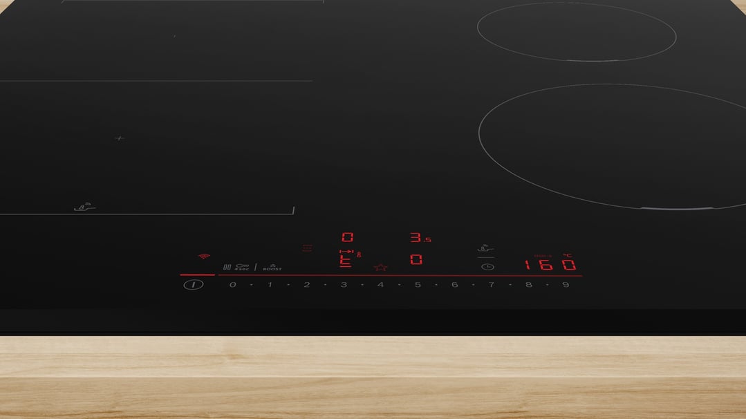 Black induction cooktop with illuminated controls on a wooden countertop