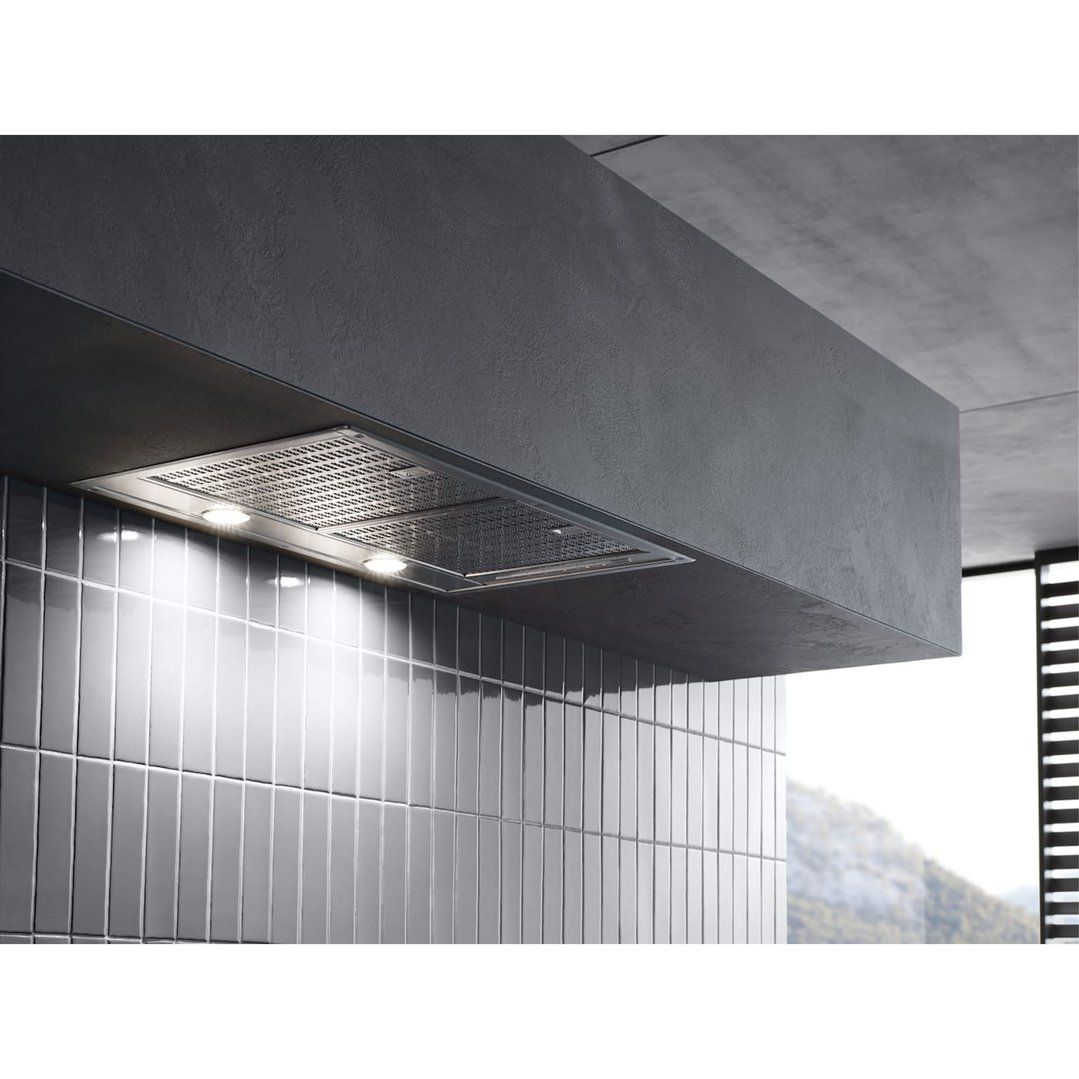 Built-in rangehood with lights on, installed above a tiled wall