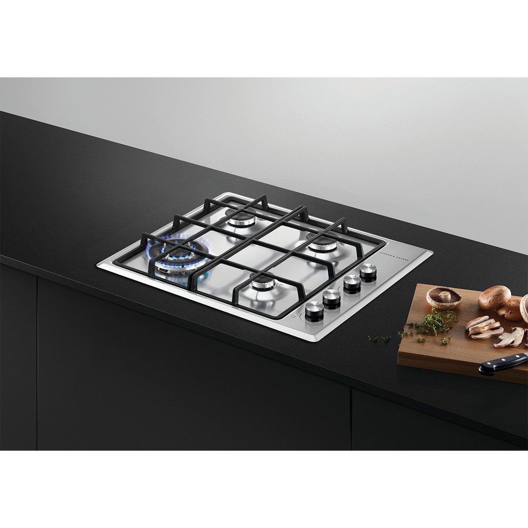 A gas cooktop with one burner lit, installed in a black kitchen counter