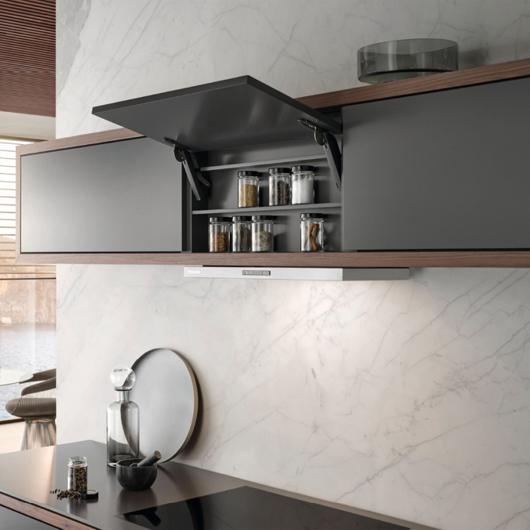 Miele rangehood installed above a cooktop in a modern kitchen with marble backsplash