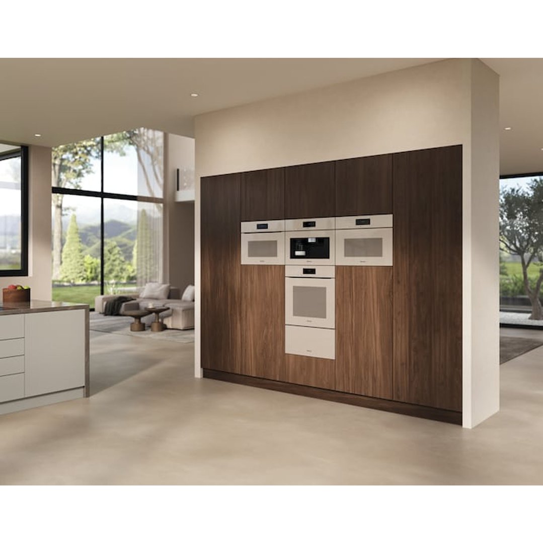 Built-in ovens and coffee machine in a modern kitchen with a living area