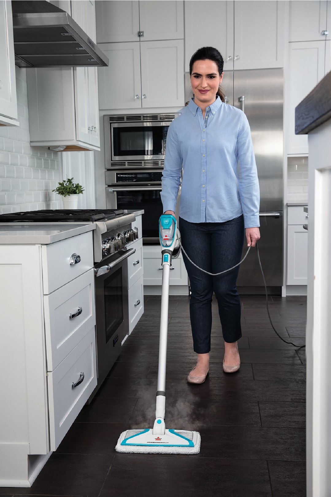 Woman using a PowerFresh Slim Steam Mop to clean a dark kitchen floor