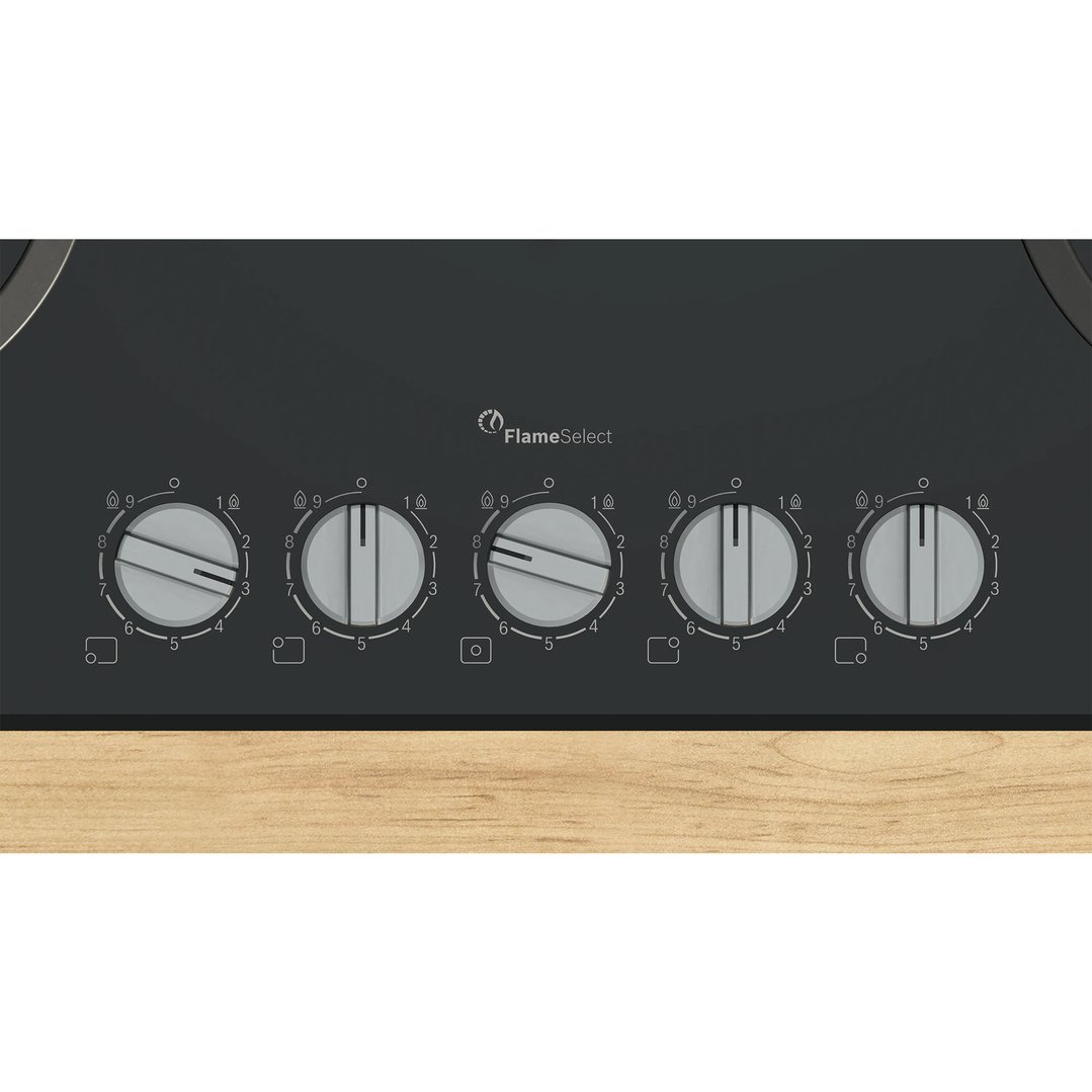 Close-up of a gas cooktop with five control knobs on a wooden countertop