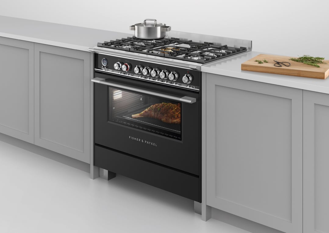 Black freestanding cooker with a leg of lamb roasting in the oven