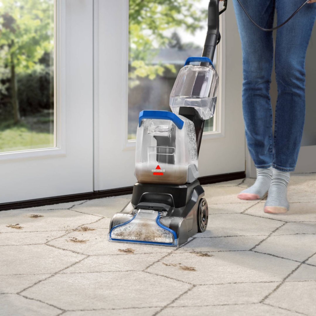 Person cleaning a dirty carpet with a BISSELL PowerForce Pet upright carpet cleaner