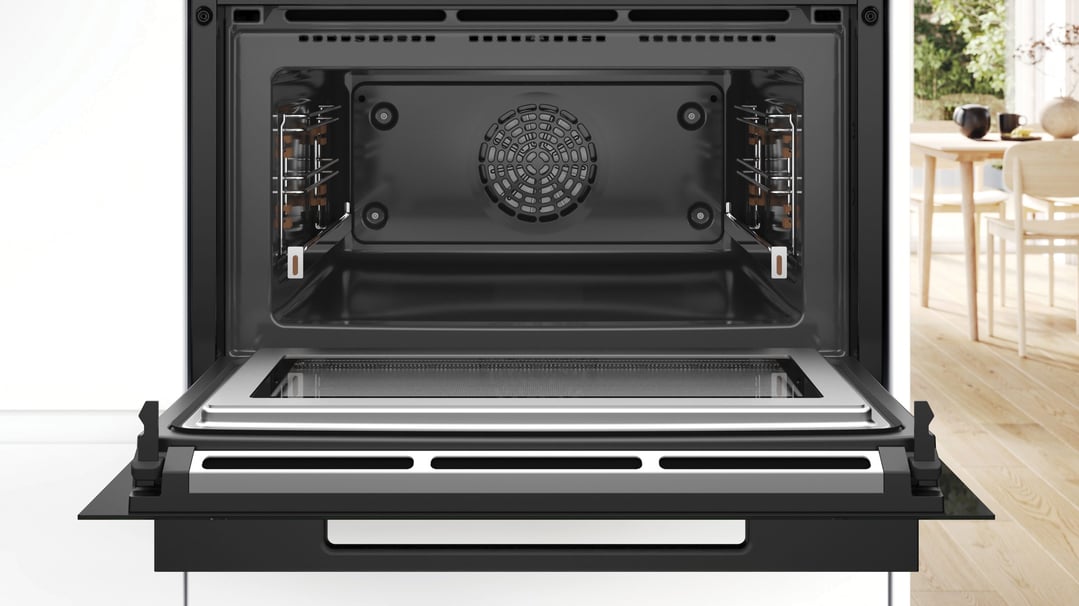 Open microwave oven with interior fan and racks, in a kitchen setting