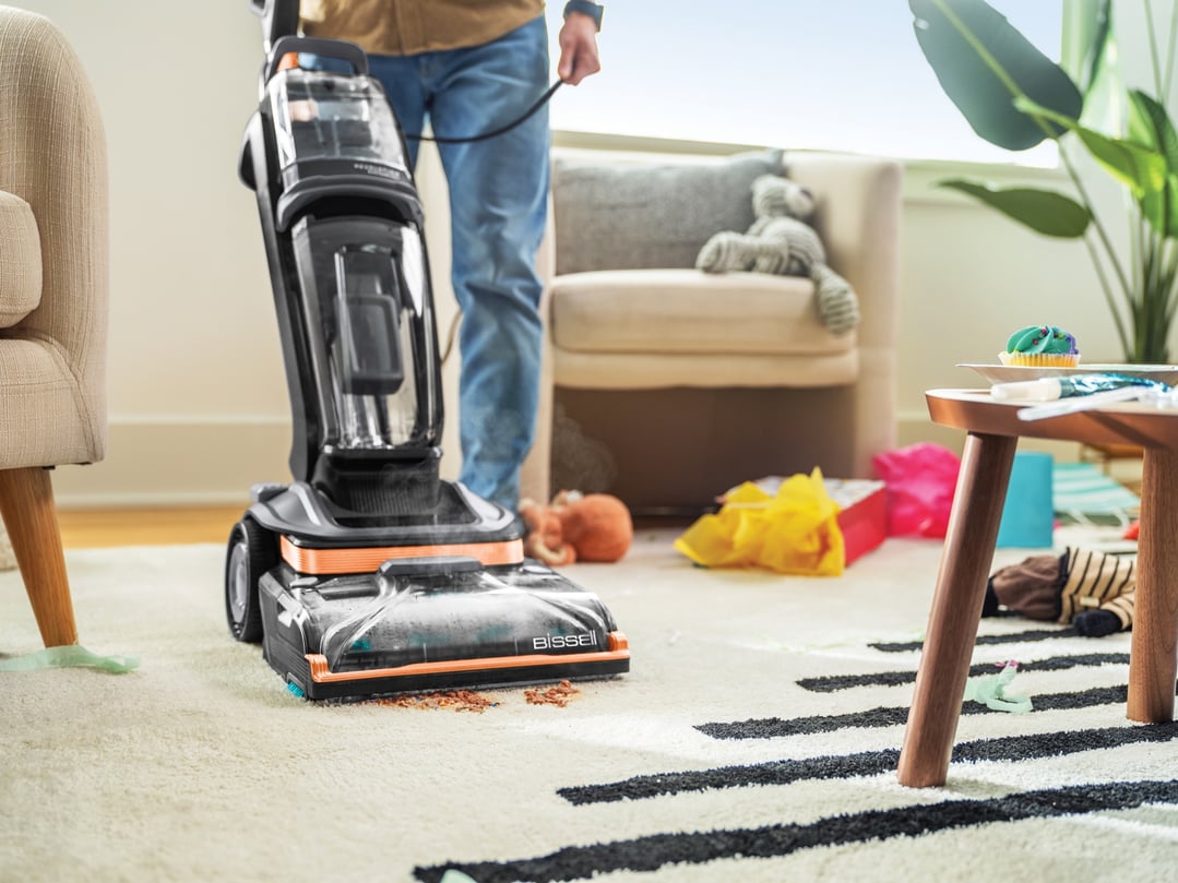 Person using a BISSELL Revolution HydroSteam vacuum cleaner on a carpet