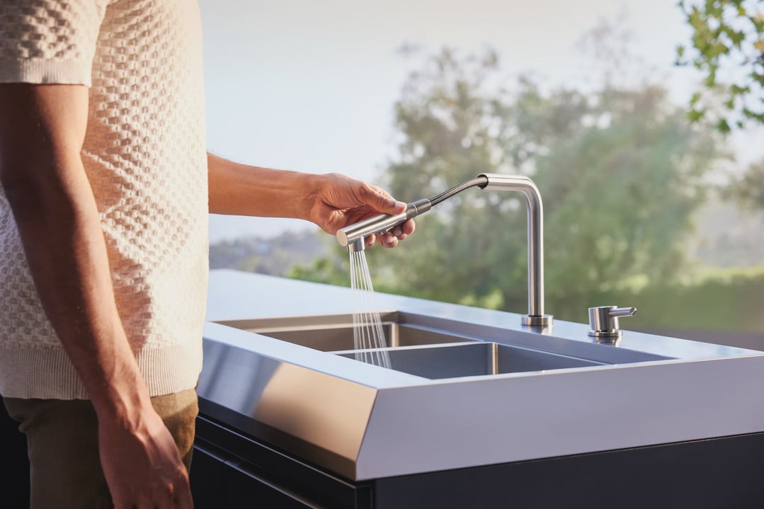 Person's hand using the spray nozzle of an outdoor kitchen sink module