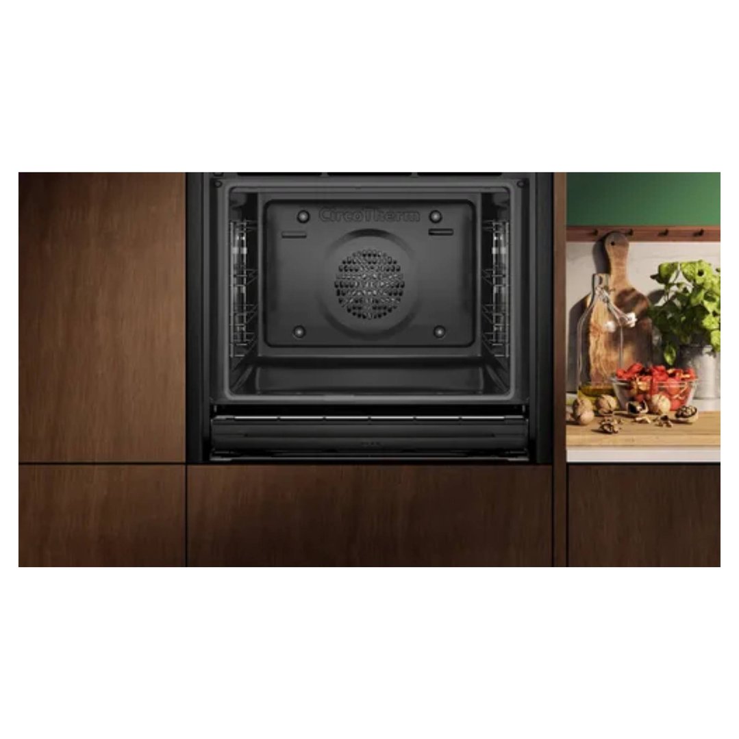 Built-in oven with an open door in a kitchen setting with wooden cabinets
