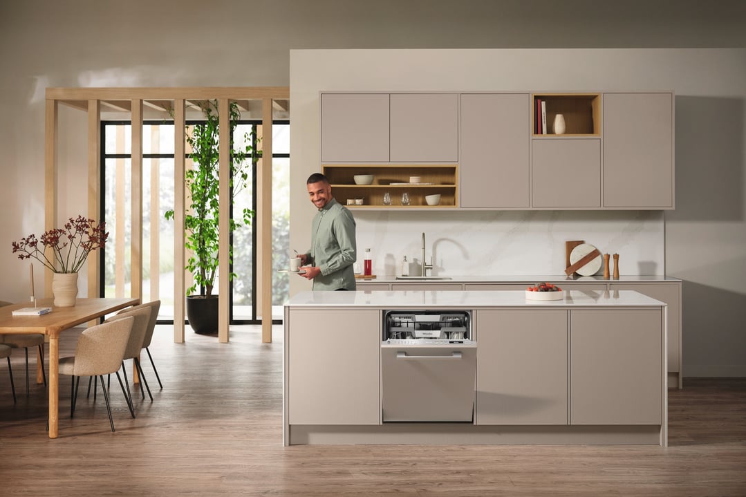 Man standing in a modern kitchen with an open integrated dishwasher