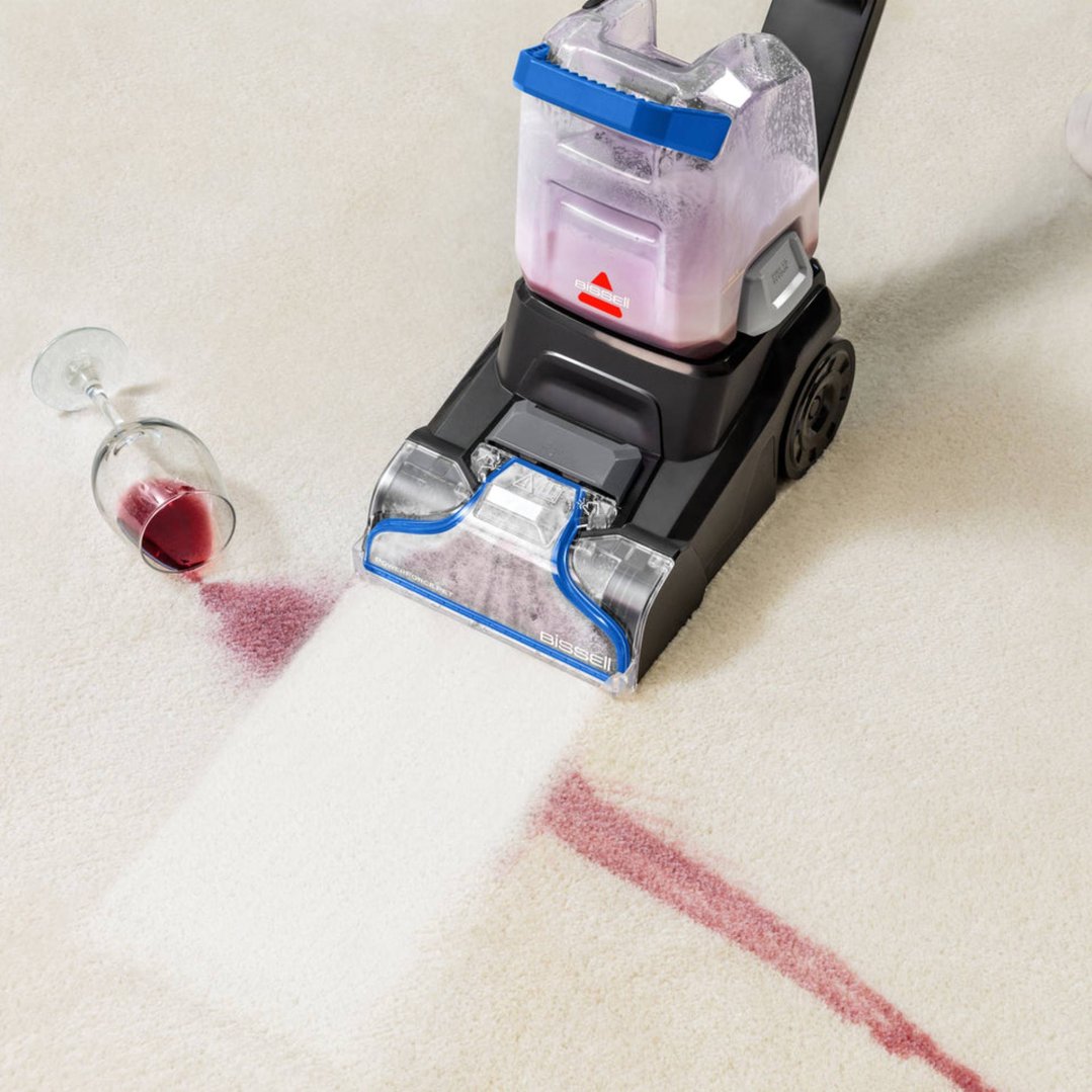 Bissell carpet cleaner cleaning red wine spill on a light-colored carpet