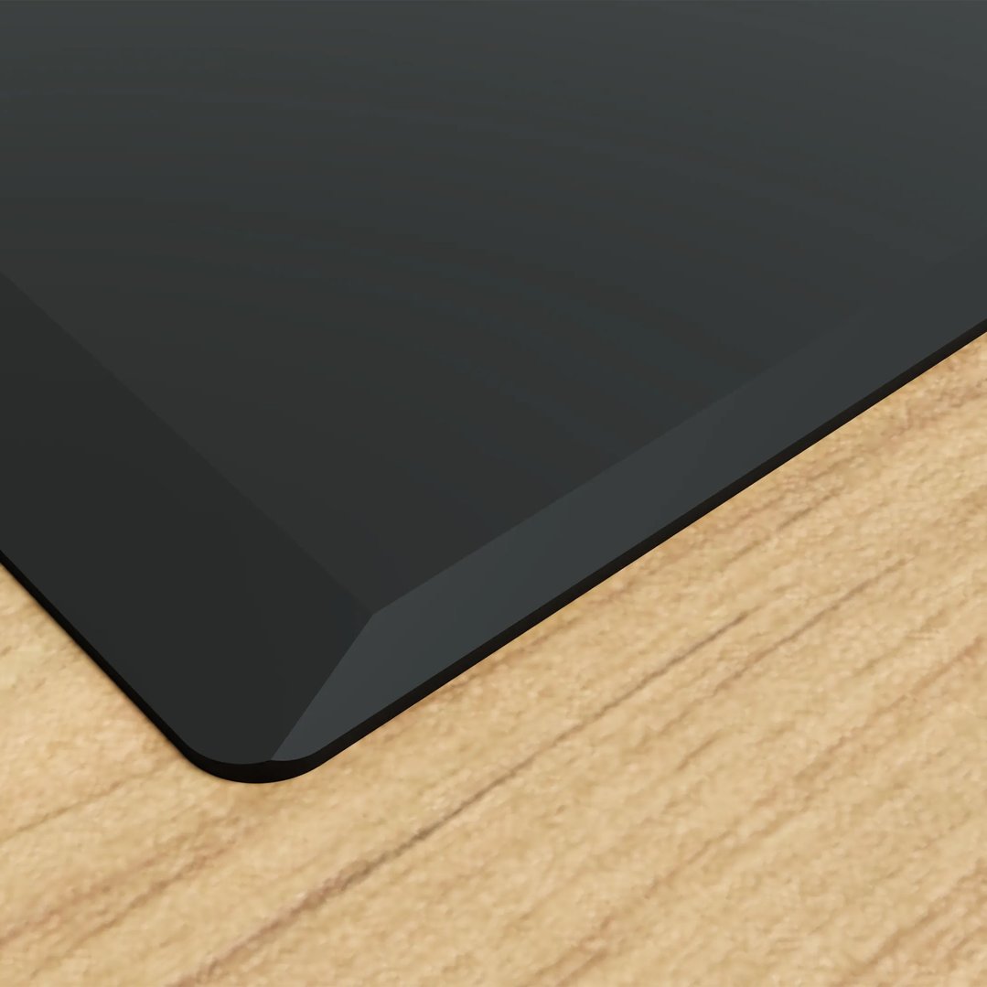 Close-up of a black glass cooktop corner on a light wooden countertop
