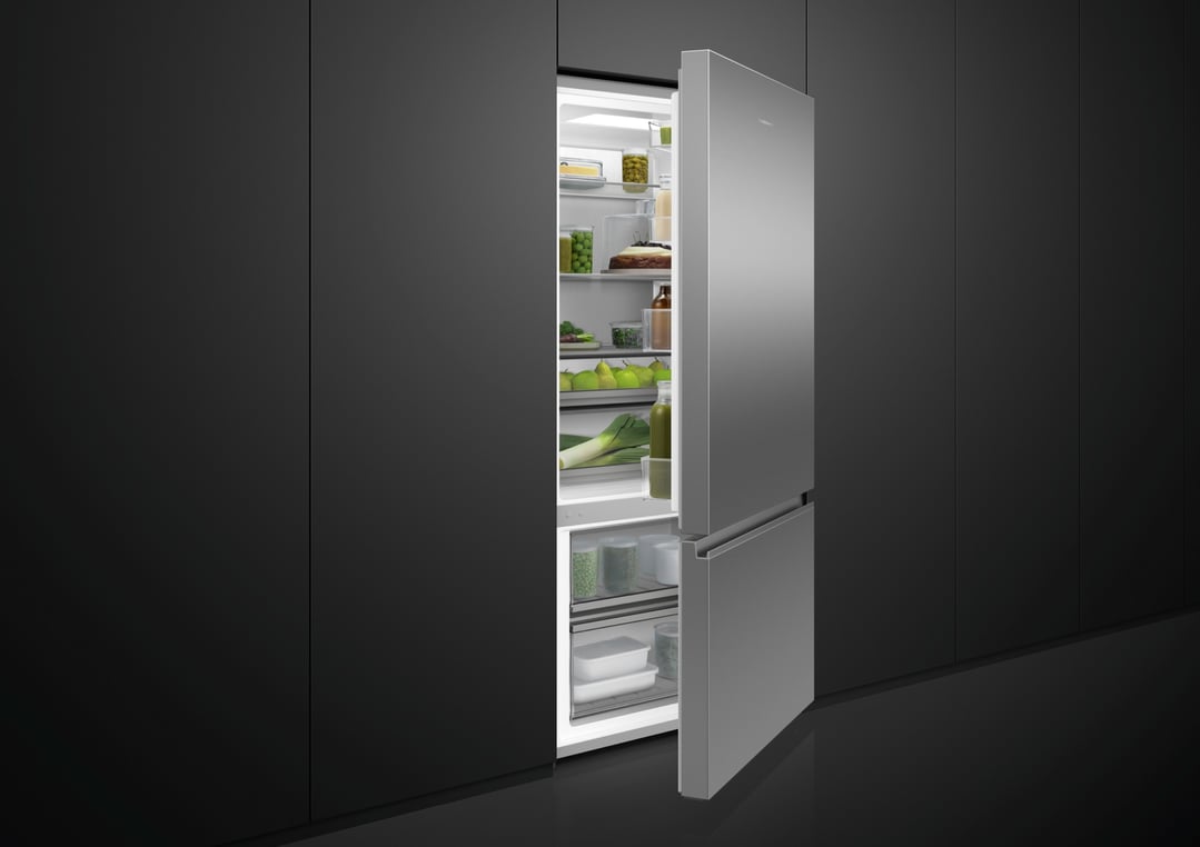 Open stainless steel bottom mount fridge in a dark modern kitchen
