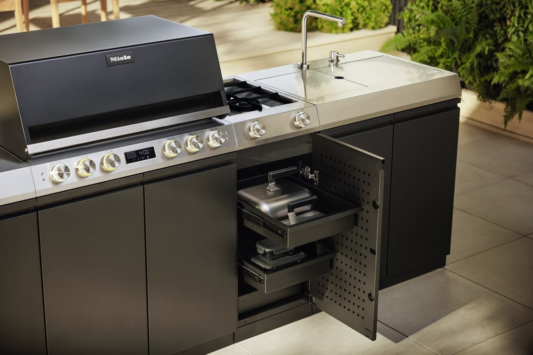 Miele outdoor cooking module with drawers in an outdoor setting with greenery